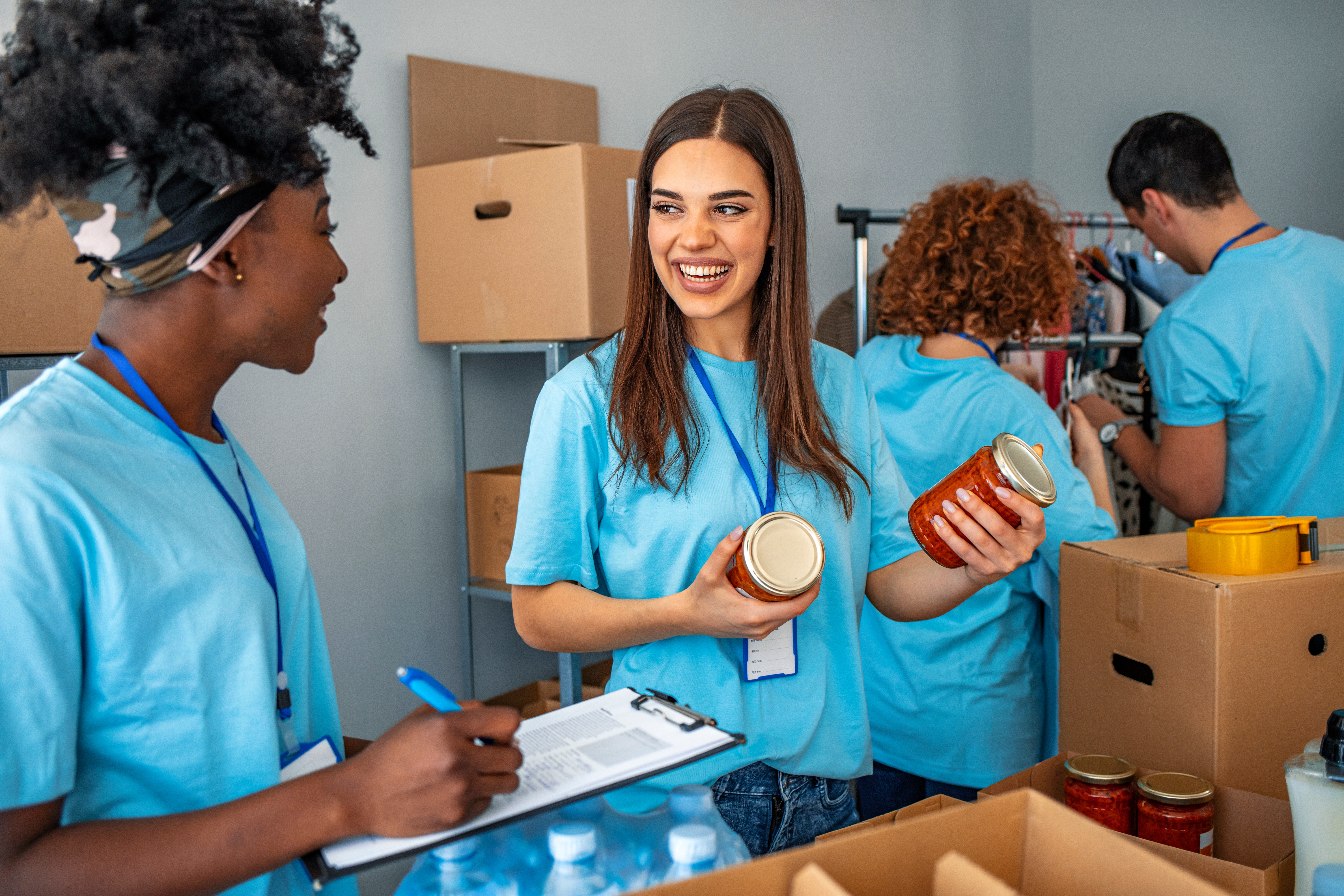 Group of people working in charitable foundation. Happy volunteer looking at donation box on a sunny day. Happy volunteer separating donations stuffs. Volunteers sort donations during food drive